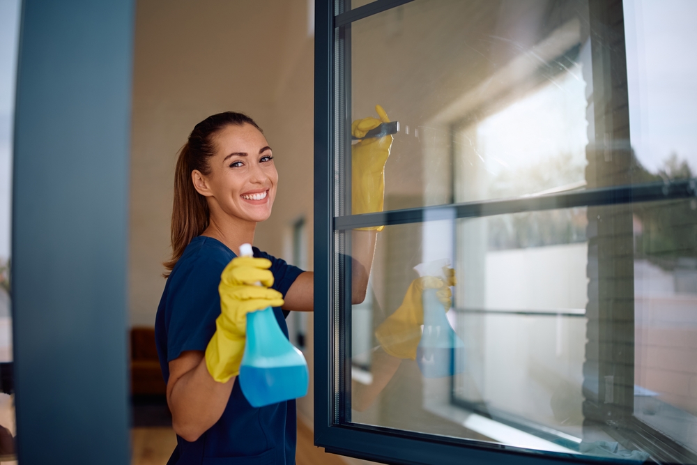 Happy,Woman,Using,Spray,Bottle,While,Cleaning,Windows,And,Looking